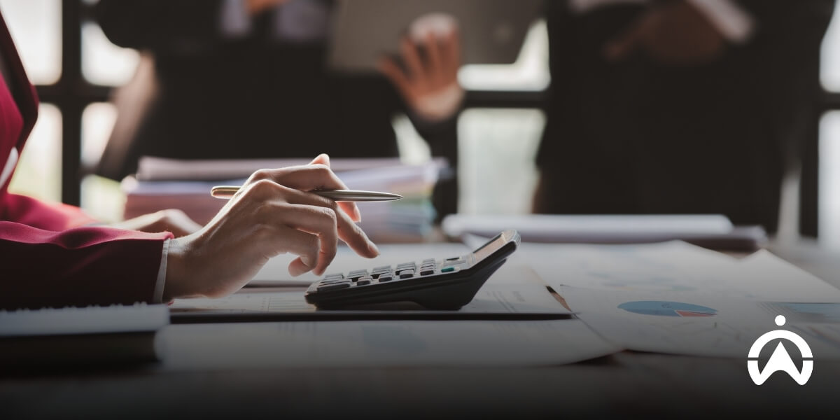 Person using a calculator with financial charts on a desk, analyzing ways to manage fleet maintenance costs.
