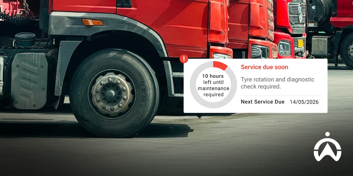 Row of red trucks parked with a fleet management technology dashboard alert showing upcoming maintenance and tyre rotation to cut operational costs.